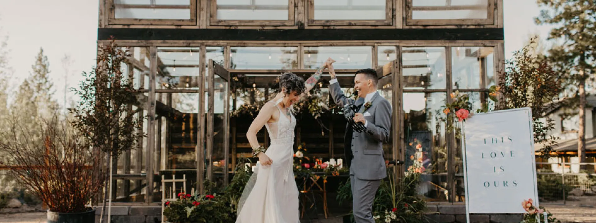 The couple stands outside a greenhouse overflowing with local blooms.