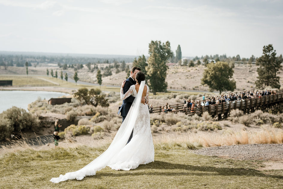 The hills and valleys of Central Oregon span beyond the couple as they pose at Brasada Ranch