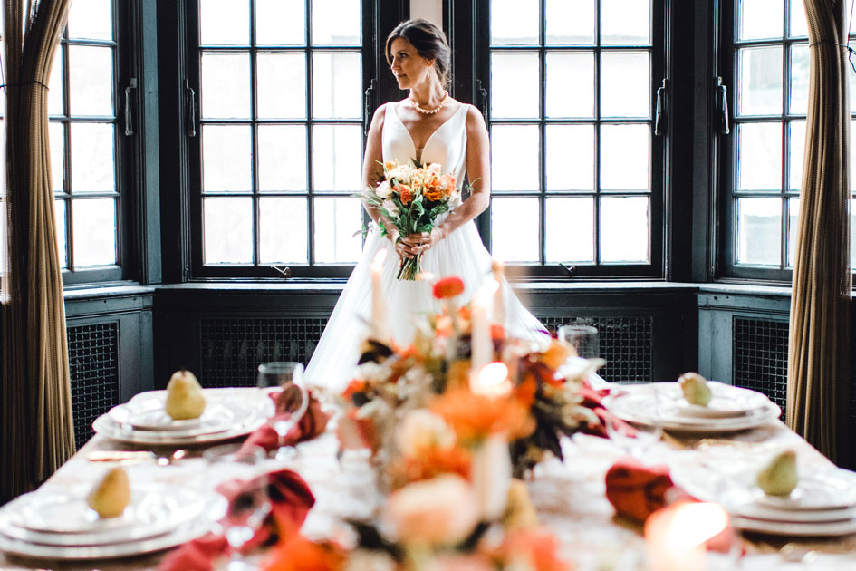 The bride stands at the head of a table bedecked with fall foliage in a grand room at The University Club of Portland